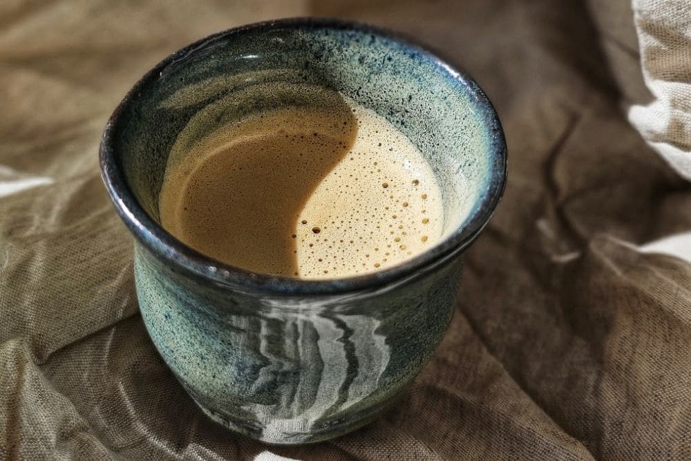 Fresh espresso coffee poured into a dark glaze ceramic cup by Whistle and Page